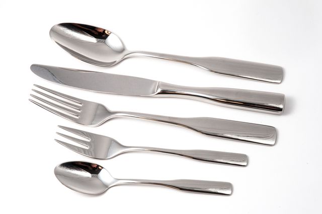Elegant stainless steel cutlery set including knife, fork, and spoons laid out on a white background. Ideal for illustrating dining, restaurant, culinary, and kitchen themes. Perfect for use in advertisements, catalogs, or articles on tableware, culinary arts, kitchenware, or home decor.