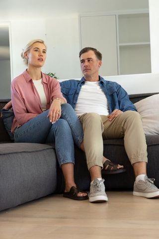 Young couple sitting and talking on modern gray sectional sofa in minimalist living room