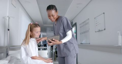 Nurse Explaining Health Materials to Young Girl in Hospital Corridor
