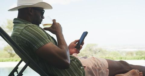 Relaxing poolside with wine and smartphone, straw hat and sunglasses, summer leisure