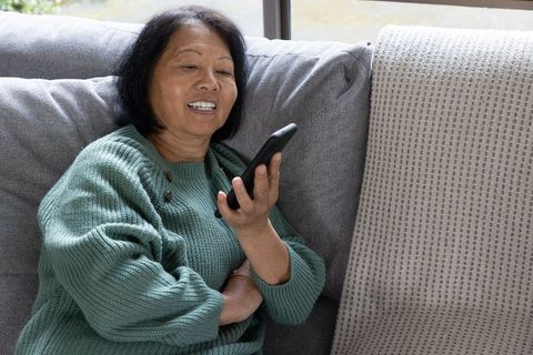 Elderly woman using smartphone for communication at home