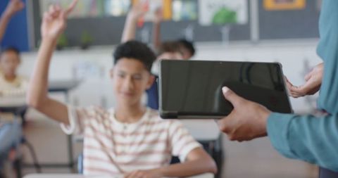 Teacher Distributing Digital Tablet to Engaged Students in Classroom