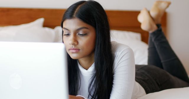 Woman using a laptop in bedroom at home