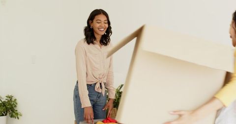 Excited woman unpacking box at new home embracing change