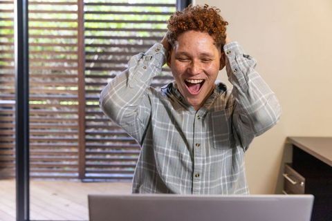 Enthusiastic Man Triumphant in Modern Office with Laptop