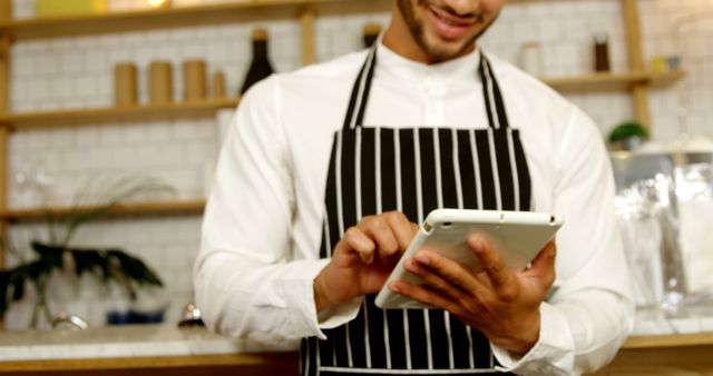 Smiling Barista Wearing Apron Using Digital Tablet in Coffee Shop - Download Free Stock Images Pikwizard.com