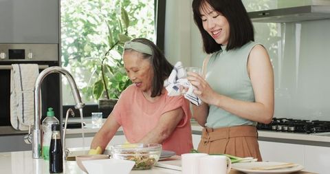 Asian mother and daughter collaborating in minimalist kitchen