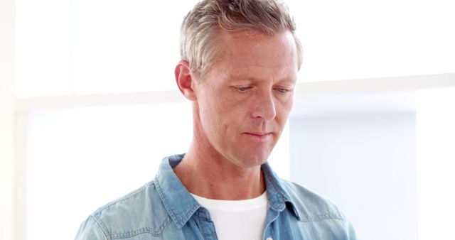 Middle Aged Man in Casual Denim Shirt Looking Down Thoughtfully - Download Free Stock Images Pikwizard.com