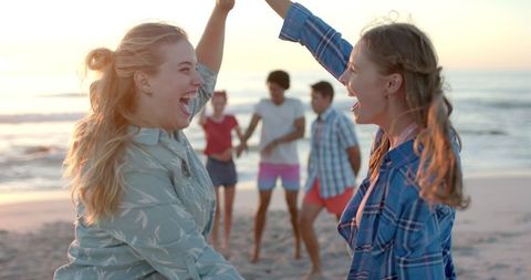 Joyful Friends Dancing at Beach Party During Sunset