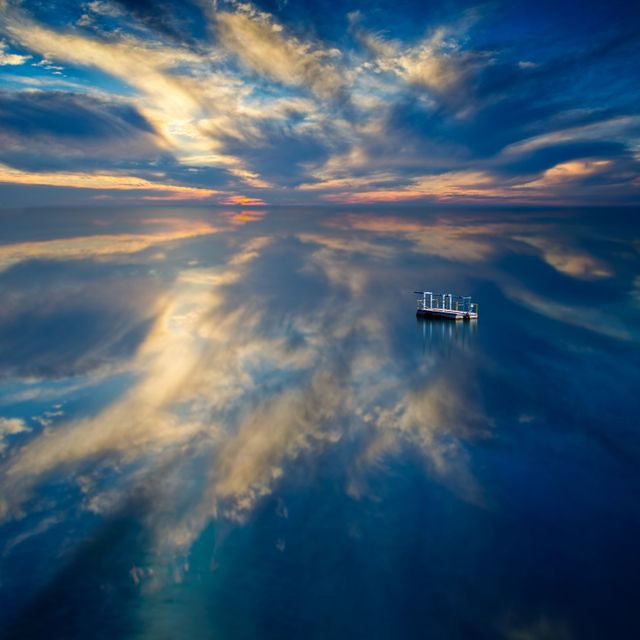 Lonely Boat on Calm Reflective Sea at Sunset with Dramatic Clouds - Download Free Stock Photos Pikwizard.com