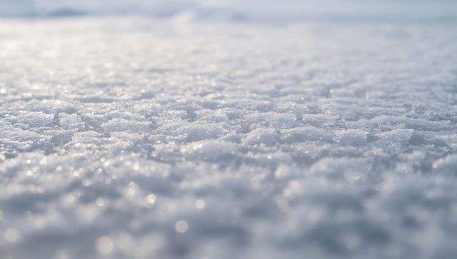 Glistening packed snow surface showing ice crystals, frost granules and sparkling bokeh
