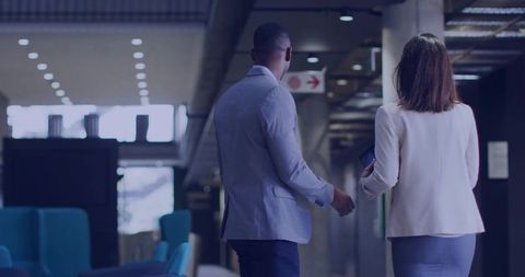 Professionals walking in modern office hallway with tablet