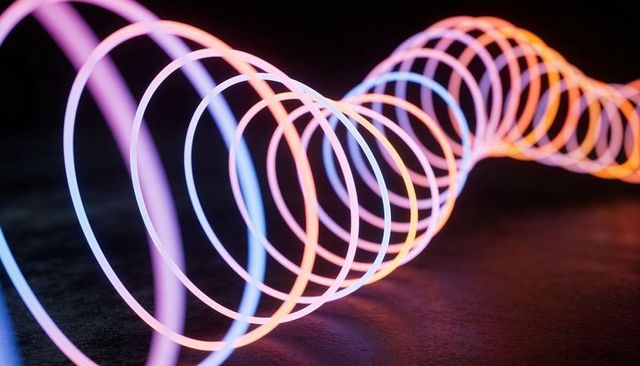 Glowing Neon Spiral Rings Stretching Across Dark Surface with Colorful Reflections