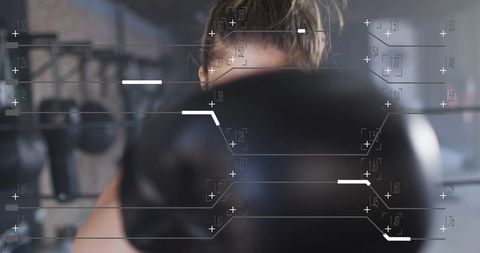 Female boxer punching toward camera with hud overlay in gym, training analytics