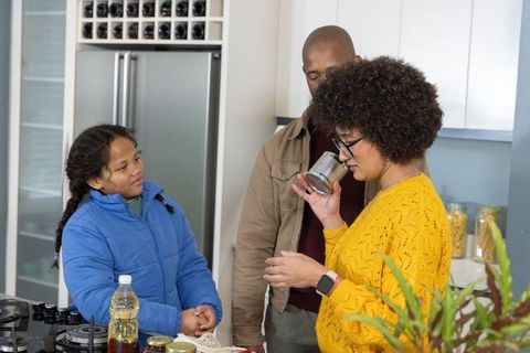 Family at kitchen island smelling canned food and organizing pantry in modern kitchen