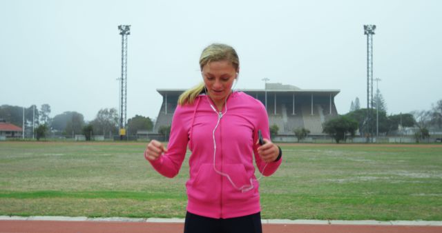Woman Exercising in Sports Stadium Wearing Pink Hoodie - Download Free Stock Images Pikwizard.com