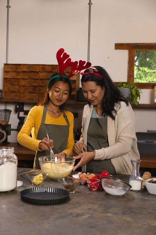 Laughing Mother and Teen Daughter Baking with Festive Antlers