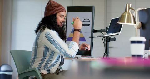 Designer sketching on vertical touchscreen with laptop arm in ergonomic modern workspace