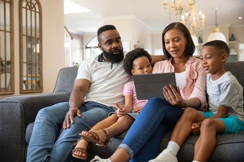 African American Family Relaxing Together on Sofa with Tablet