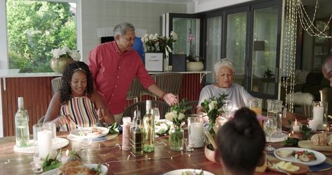 Multigenerational diverse family celebrating retirement dinner cozy candlelit wooden table