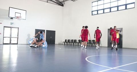 Diverse basketball players consoling teammate on indoor court