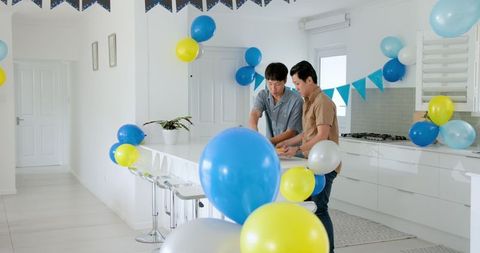 Two men decorating kitchen with balloons for a celebration