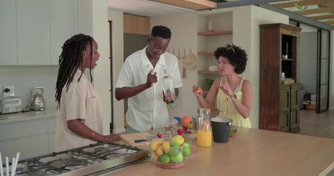 African American Friends Chatting Around Kitchen Island Preparing Fresh Juice and Fruit