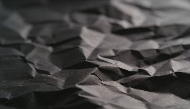 Crumpled Black Paper Texture Showing Deep Folds and Moody Lighting for Minimalist Use