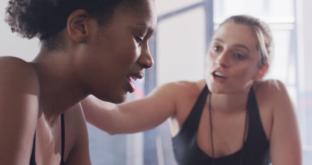Image of diverse female fitness trainer talking with exhausted woman after working out at a gym. Exercise, fitness and healthy lifestyle.
