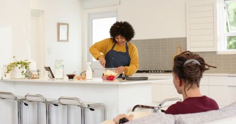 Couple baking together in modern kitchen, woman stirring batter at island