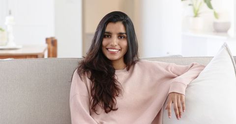 Smiling woman relaxing on sofisticated sofa in bright living room