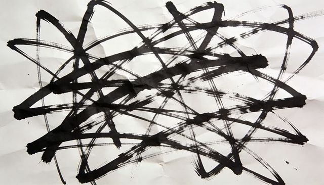 Gestural black-ink brushstrokes on creased white paper creating bold monochrome texture