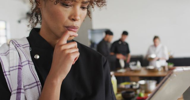 Focused Female Chef Contemplating Recipe in Busy Kitchen - Download Free Stock Images Pikwizard.com