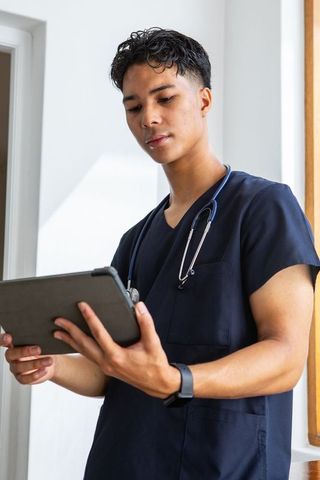 Asian male healthcare professional reviewing tablet in modern clinic