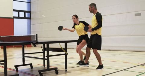 Teammates Practicing Table Tennis Intensely in Modern Gymnasium
