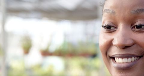 Close-Up of Smiling Woman in Greenhouse, Embracing Nature