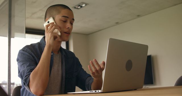 Young Professional Talking on Phone while Working on Laptop - Download Free Stock Images Pikwizard.com