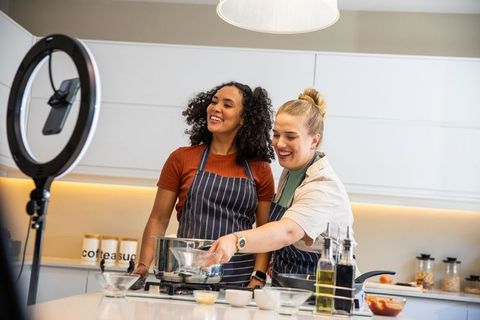 Friends cooking together while filming culinary show