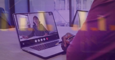 Presenting remote conference on laptop while participant holding pen and taking notes