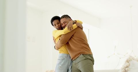 Diverse Couple Sharing Emotional Hug in Contemporary Living Room