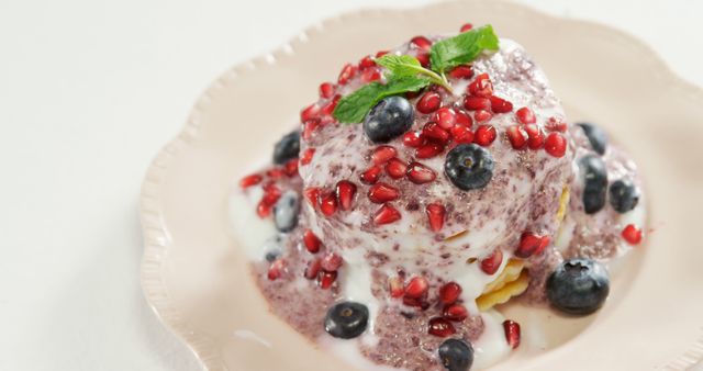 Juicy blueberries, colorful pomegranate seeds, and creamy Greek yogurt over a stack of pancakes. Perfect for illustrating healthy breakfast, brunch ideas, or dessert recipes. Could be used in food blogs, café menus, or nutritional advertisements.