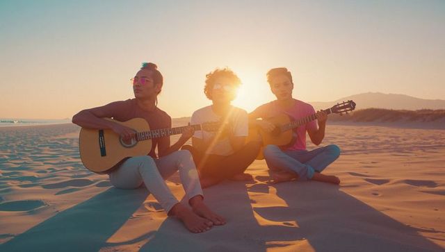 Friends Playing Guitars on Beach During Sunset