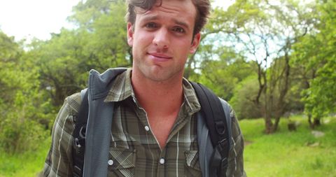 Young Man Hiking in Green Landscape with Backpack and Casual Attire