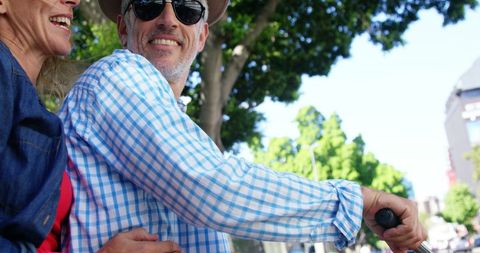 Laughing Mature Couple Riding Bike in Urban Park