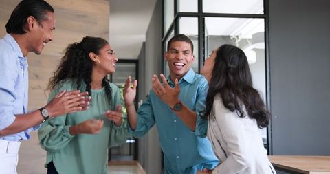 Diverse Team Celebrating Achievement with High Fives in Office
