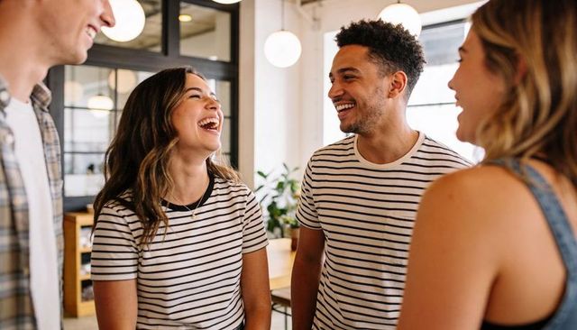 Young coworkers laughing and chatting in modern coworking workspace wearing striped shirts
