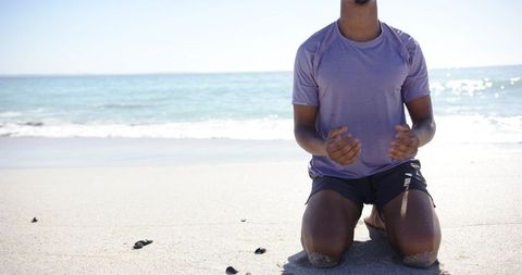 African american man kneeling on beach guiding baby sea turtles toward ocean conservation