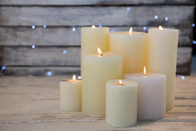 Burning candles on a wooden plank create a warm and cozy ambiance, perfect for Christmas and holiday decorations. Ideal for use in festive greeting cards, home decor inspiration, relaxation and wellness promotions, or rustic-themed event planning.