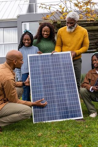 African american family installing solar panel in backyard discussing renewable energy
