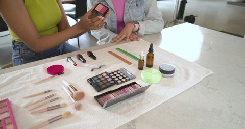 Diverse women demonstrating makeup palettes and brushes during beauty consultation